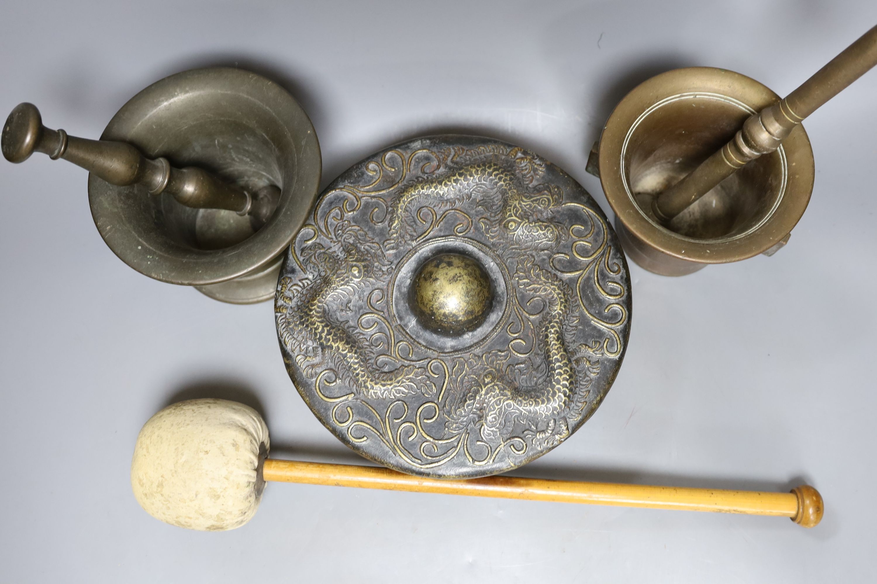 Two pestles and mortars and a Chinese gong with beater, gong 21 cms wide.